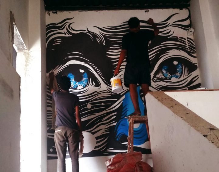 Aftab painting a mural with Inderjeet