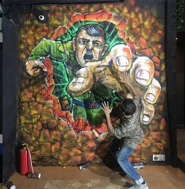 guy posing at selfie point of graffit art on hitler coming out of wall for lounge blacklisted 2